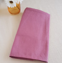 Load image into Gallery viewer, Folded pink fabric on a light beige surface with a small vase of flowers.