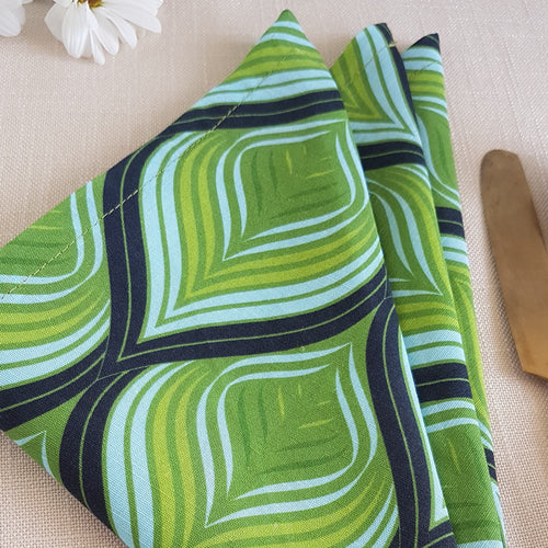 Green, aqua, and black swirl design on a linen–cotton cocktail napkin with crisp, tailored edges