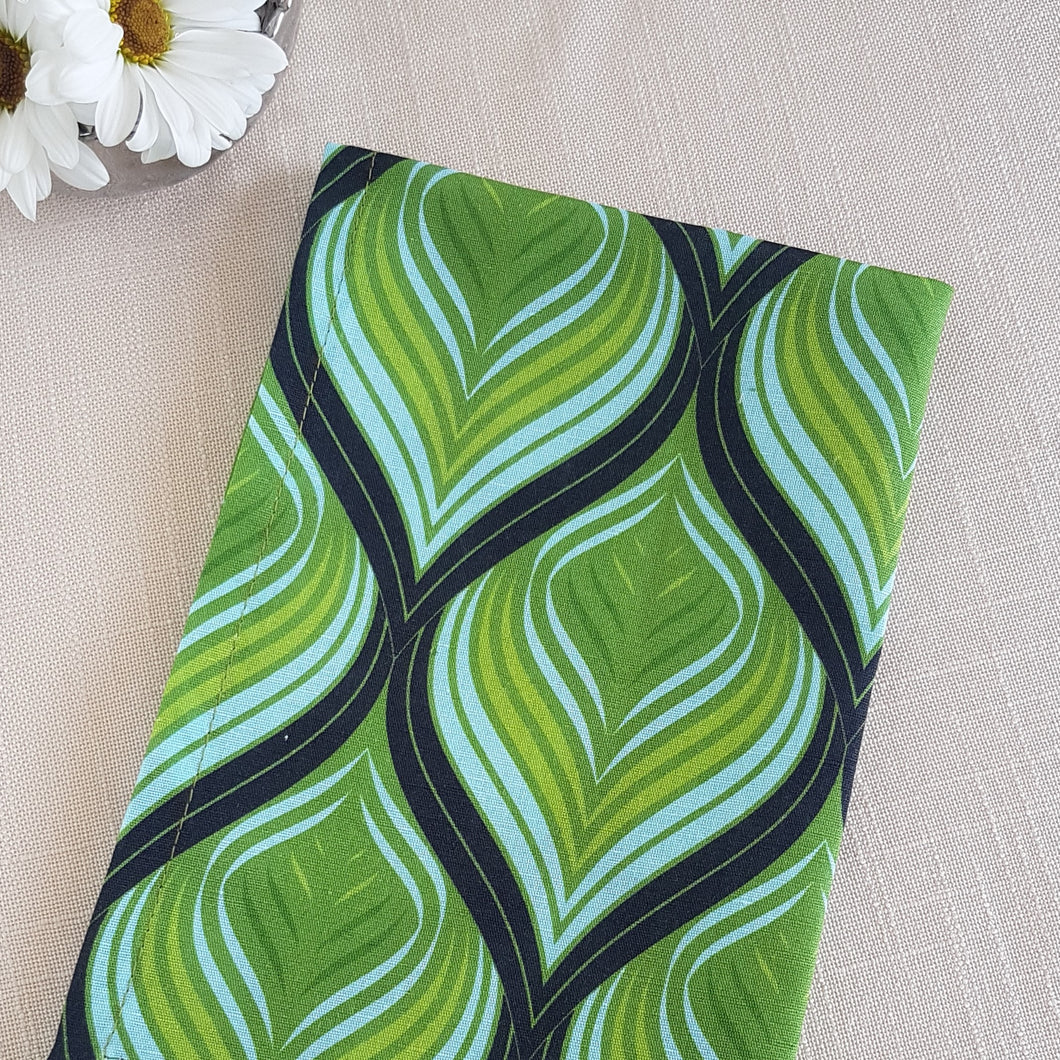 Green, aqua, and black swirl design on a linen–cotton cocktail napkin with crisp, tailored edges