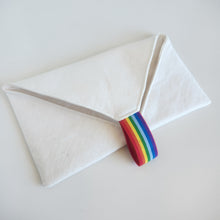 Load image into Gallery viewer, White linen cutlery wrap pouch with a rainbow striped elastic loop on a light gray background