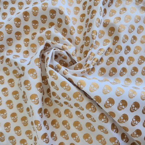 Fabric with gold skull pattern on a white background